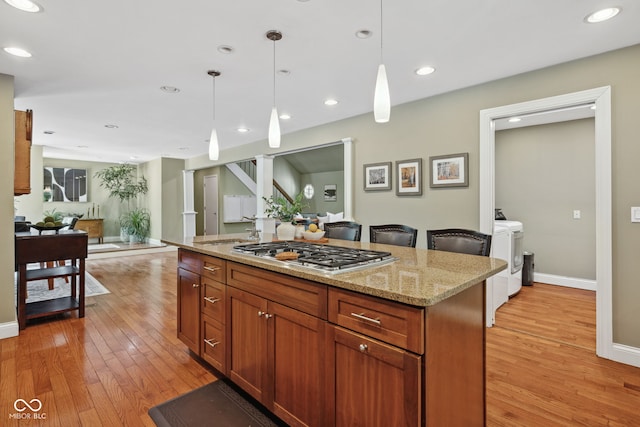 8330 Claridge Rd, Indianapolis, IN 46260 - kitchen featuring stainless steel gas stovetop, light wood-style floors, washer and clothes dryer, open floor plan, and recessed lighting