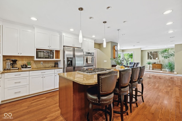 8330 Claridge Rd, Indianapolis, IN 46260 - kitchen featuring stainless steel appliances, light wood-style floors, light stone countertops, a center island, and a kitchen bar
