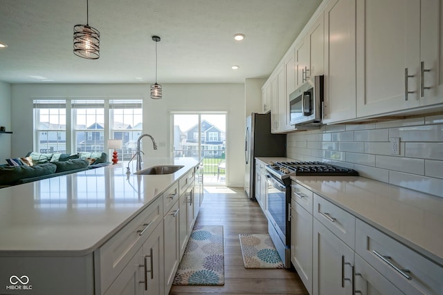 kitchen featuring stainless steel appliances, a sink, decorative backsplash, recessed lighting, and light countertops