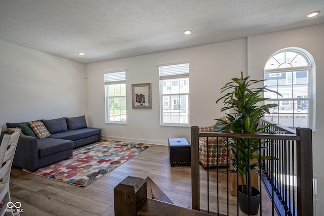living area with plenty of natural light, wood finished floors, recessed lighting, baseboards, and a textured ceiling