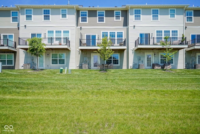 rear view of property featuring a yard and cooling unit