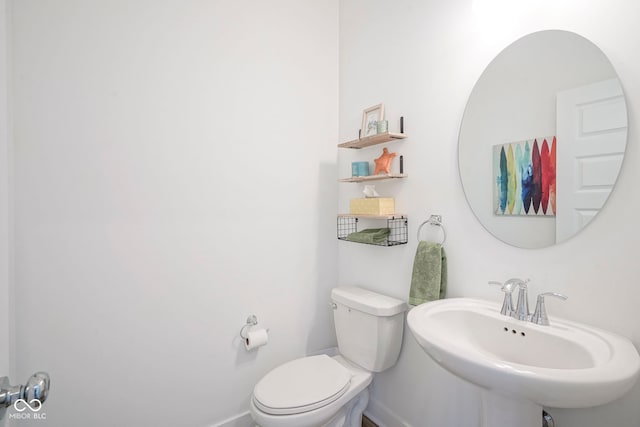 bathroom with a sink, toilet, and baseboards