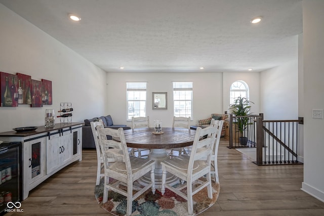 dining space featuring wood finished floors, recessed lighting, a textured ceiling, and baseboards