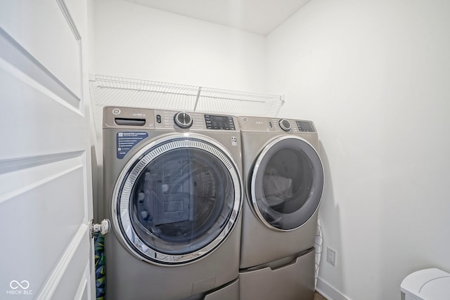 clothes washing area with separate washer and dryer and baseboards