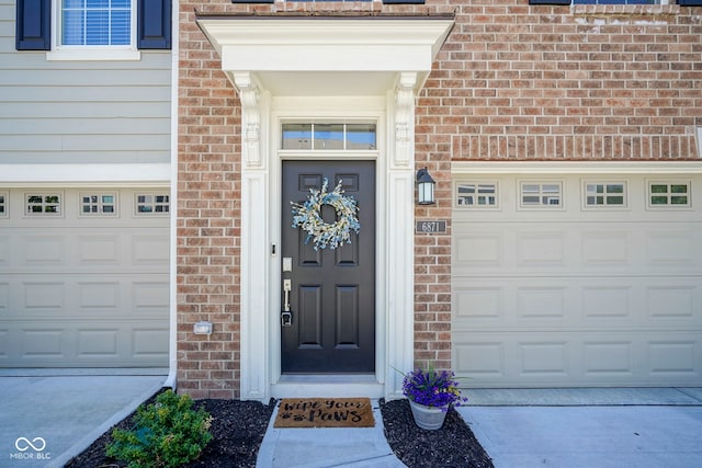 view of exterior entry featuring concrete driveway and brick siding