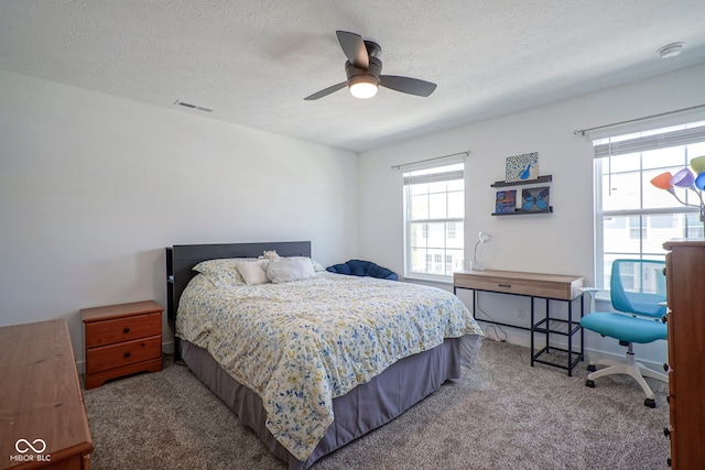 bedroom featuring carpet flooring, multiple windows, a textured ceiling, and ceiling fan
