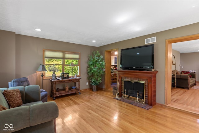 living area featuring wood finished floors, recessed lighting, and a brick fireplace