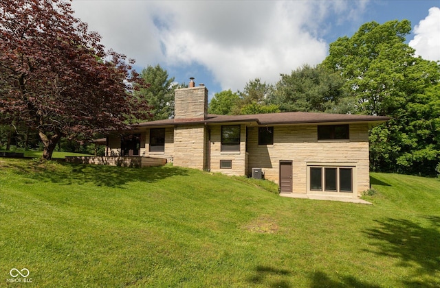 rear view of property with a chimney, stone siding, and a yard