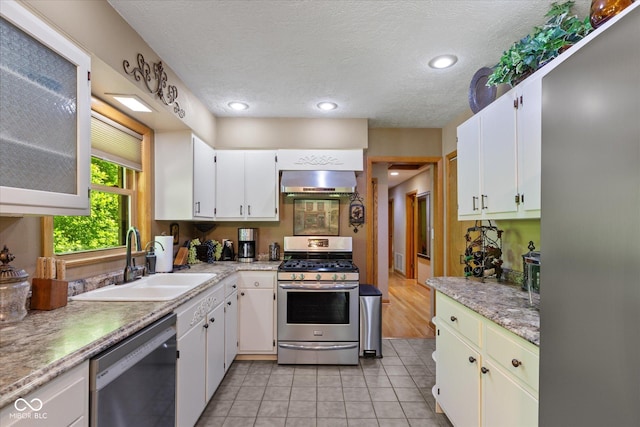 kitchen with appliances with stainless steel finishes, a sink, extractor fan, light countertops, and a textured ceiling