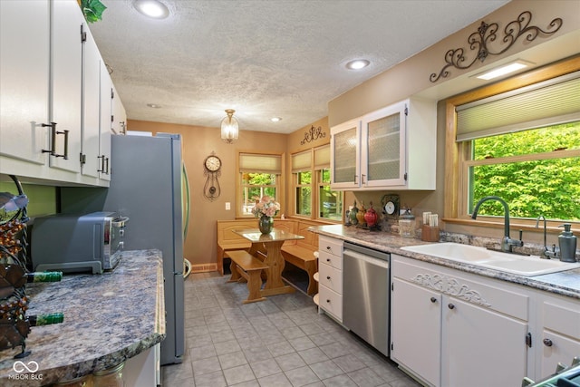kitchen featuring appliances with stainless steel finishes, a sink, white cabinets, a textured ceiling, and light tile patterned flooring