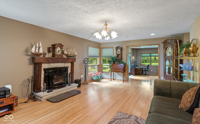 living room featuring a chandelier, wood finished floors, a textured ceiling, baseboards, and a fireplace