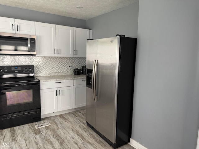 322 S Rural St, Indianapolis, IN 46201 - kitchen featuring appliances with stainless steel finishes, light wood-type flooring, light countertops, white cabinets, and decorative backsplash