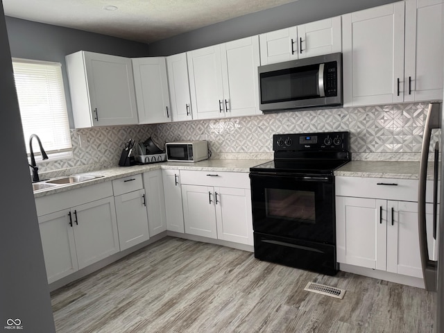 322 S Rural St, Indianapolis, IN 46201 - kitchen with stainless steel microwave, electric range, a sink, light wood-style floors, and light countertops