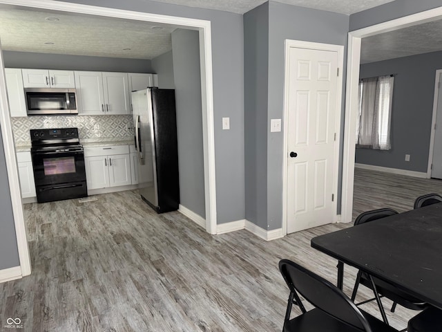 322 S Rural St, Indianapolis, IN 46201 - kitchen with stainless steel appliances, white cabinetry, backsplash, baseboards, and a textured ceiling