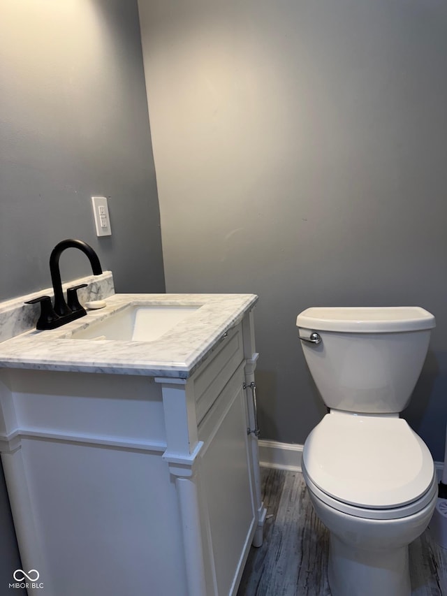 322 S Rural St, Indianapolis, IN 46201 - half bathroom featuring vanity, toilet, wood finished floors, and baseboards
