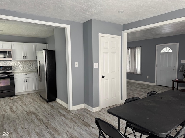 322 S Rural St, Indianapolis, IN 46201 - kitchen featuring stainless steel appliances, white cabinets, light wood finished floors, a textured ceiling, and baseboards