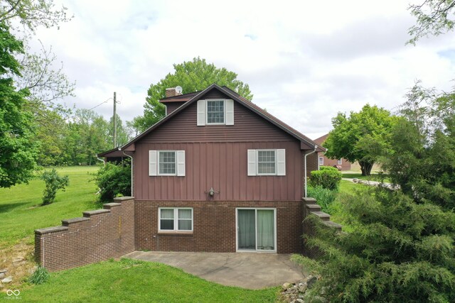3654 W Mecca Rd, Rockville, IN 47872 - back of house featuring a chimney, a patio, board and batten siding, a lawn, and brick siding
