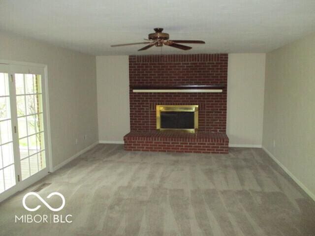 4667 Sundance Trl, Indianapolis, IN 46239 - unfurnished living room featuring ceiling fan, baseboards, carpet floors, and a brick fireplace