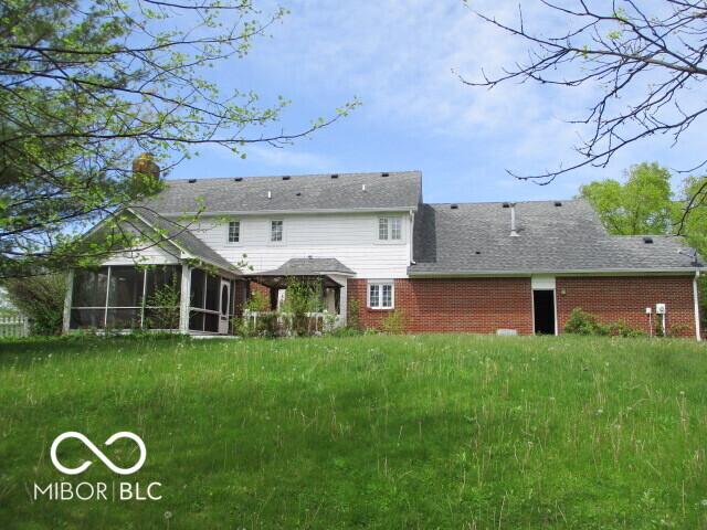 4667 Sundance Trl, Indianapolis, IN 46239 - back of property featuring a sunroom, brick siding, and a chimney