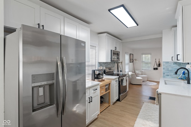 1802 E 66th St, Indianapolis, IN 46220 - kitchen with stainless steel appliances, a sink, tasteful backsplash, light countertops, and crown molding