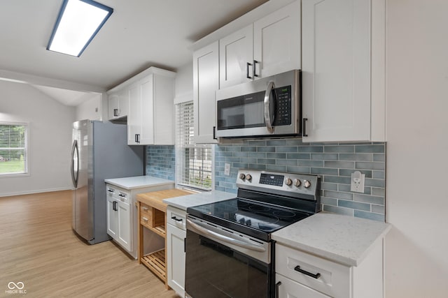 1802 E 66th St, Indianapolis, IN 46220 - kitchen featuring stainless steel appliances, lofted ceiling, light wood-style floors, white cabinetry, and backsplash
