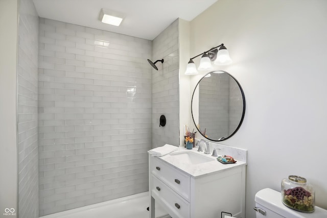 full bathroom featuring toilet, tiled shower, and vanity