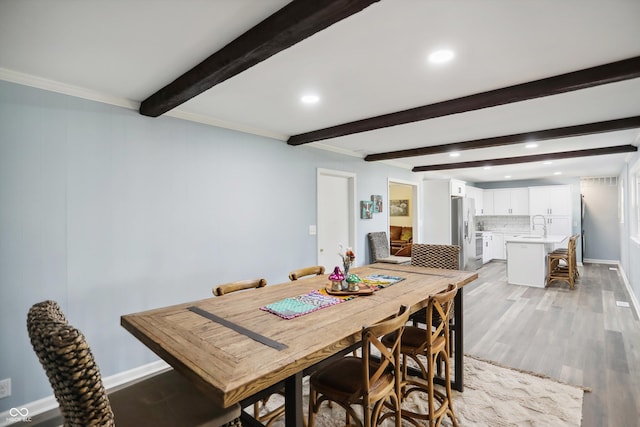 dining room with beam ceiling, recessed lighting, light wood-type flooring, baseboards, and crown molding