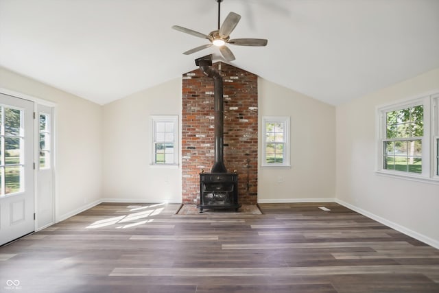 unfurnished living room with a wood stove, wood finished floors, ceiling fan, vaulted ceiling, and baseboards