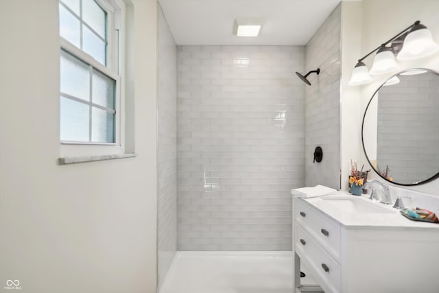 bathroom with a tile shower and vanity