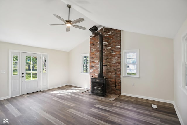 unfurnished living room with a wood stove, wood finished floors, vaulted ceiling, a ceiling fan, and baseboards
