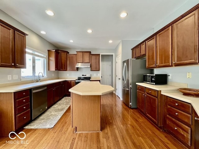 kitchen featuring stainless steel appliances, under cabinet range hood, wood finished floors, a center island, and recessed lighting