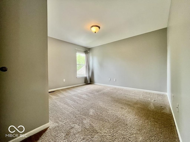 carpeted empty room featuring baseboards