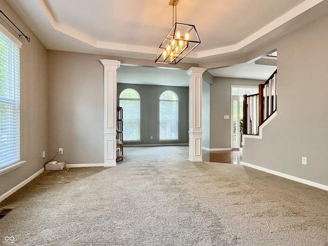 empty room featuring decorative columns, carpet floors, a raised ceiling, baseboards, and stairway