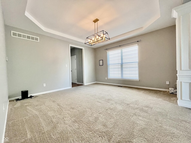 unfurnished room featuring a raised ceiling, carpet flooring, baseboards, and a chandelier