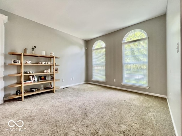 spare room featuring carpet floors and baseboards