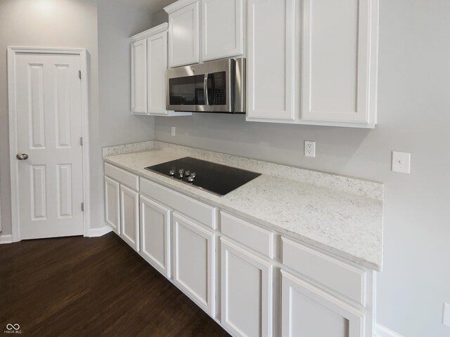 18230 Sandy Cove Ln, Westfield, IN 46074 - kitchen with stainless steel microwave, black electric cooktop, dark wood finished floors, white cabinetry, and light stone countertops