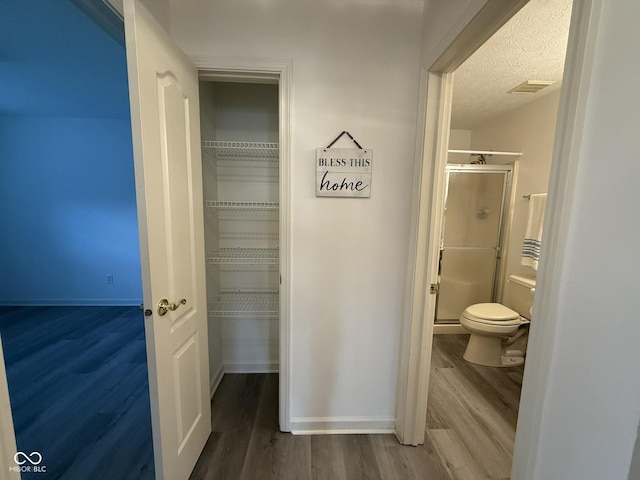 11523 Coastal Way, Indianapolis, IN 46229 - full bathroom with wood finished floors, a stall shower, baseboards, a textured ceiling, and toilet