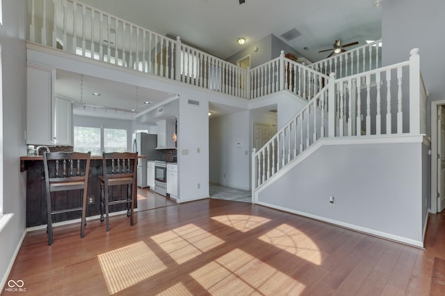 6542 E Edna Mills Dr, Camby, IN 46113 - living room featuring wood finished floors, ceiling fan, a towering ceiling, stairway, and baseboards
