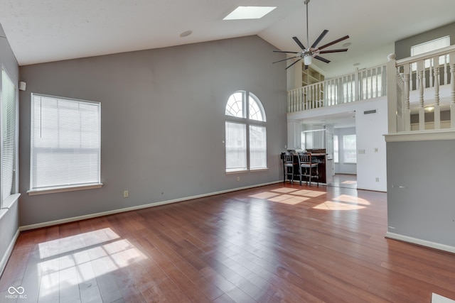 6542 E Edna Mills Dr, Camby, IN 46113 - unfurnished living room with ceiling fan, a skylight, high vaulted ceiling, wood finished floors, and baseboards