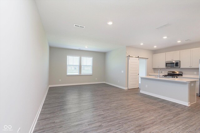 9604 Beckett St, Avon, IN 46123 - kitchen featuring stainless steel appliances, a barn door, wood finished floors, recessed lighting, and light countertops