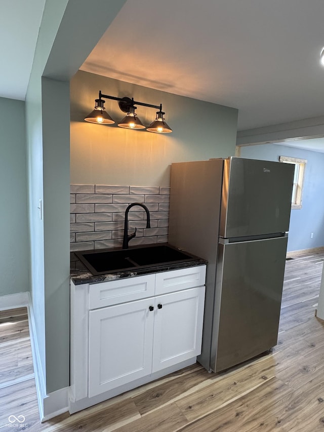 671 E Bethel Rd, Attica, IN 47918 - kitchen featuring freestanding refrigerator, a sink, backsplash, white cabinets, and light wood-style floors