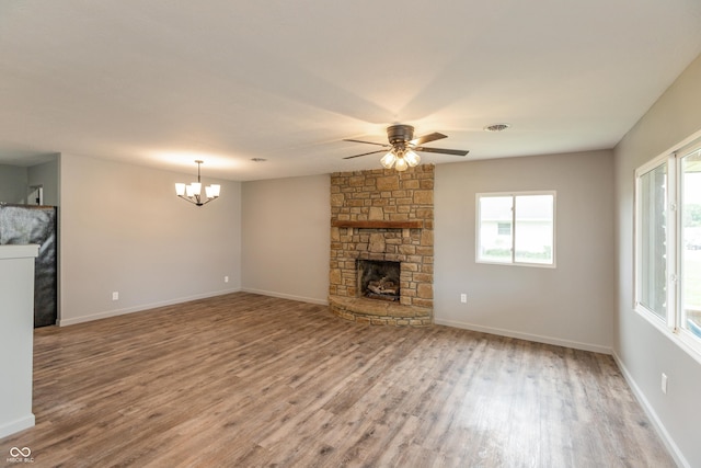 521 Sunset Dr, Edinburgh, IN 46124 - unfurnished living room with wood finished floors, a ceiling fan, a chandelier, and a stone fireplace