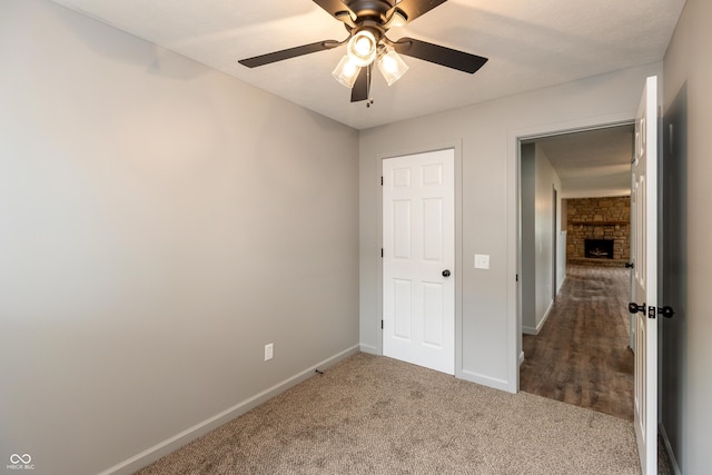 521 Sunset Dr, Edinburgh, IN 46124 - unfurnished bedroom with carpet, baseboards, a stone fireplace, and ceiling fan