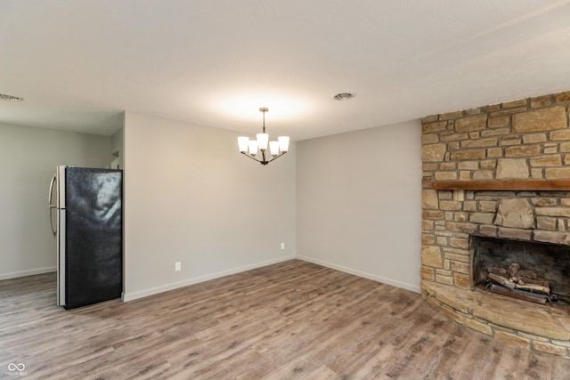 521 Sunset Dr, Edinburgh, IN 46124 - unfurnished living room with wood finished floors, baseboards, a fireplace, and a chandelier