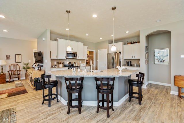 9166 Lieven St, Avon, IN 46123 - kitchen featuring appliances with stainless steel finishes, light wood-type flooring, a large island with sink, a sink, and decorative backsplash