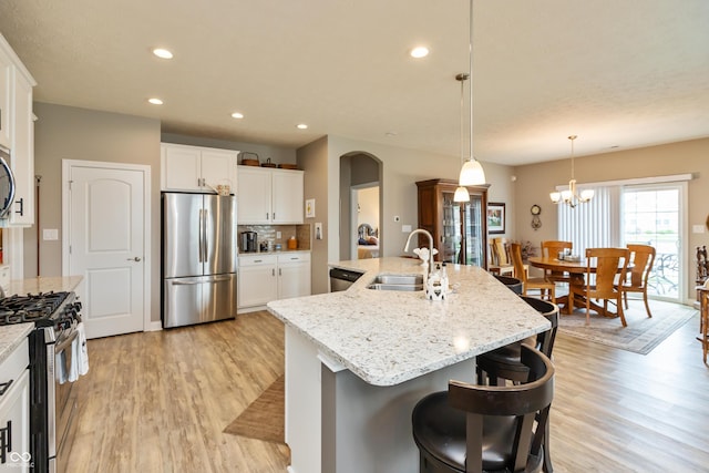 9166 Lieven St, Avon, IN 46123 - kitchen featuring stainless steel appliances, a sink, light wood-style flooring, an island with sink, and arched walkways