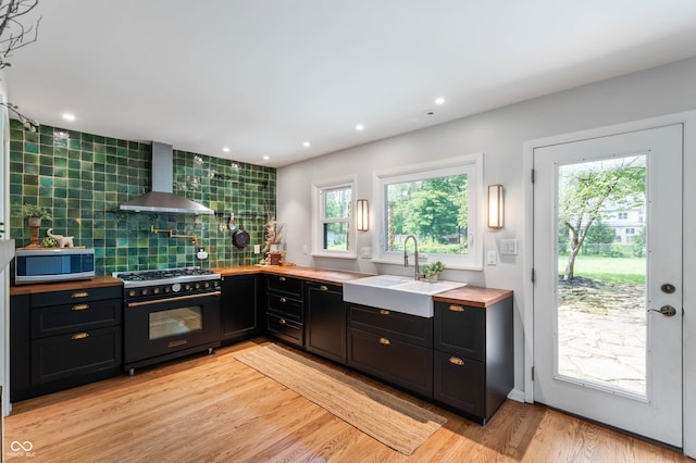 2120 Wynnedale Rd, Indianapolis, IN 46228 - kitchen with wall chimney range hood, high end black range, stainless steel microwave, dark cabinets, and healthy amount of natural light