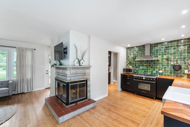 2120 Wynnedale Rd, Indianapolis, IN 46228 - kitchen with high end stove, wall chimney exhaust hood, wooden counters, stainless steel microwave, and recessed lighting