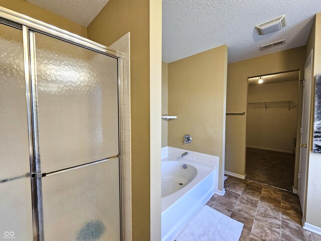 10836 Zimmerman Ln, Indianapolis, IN 46231 - full bath with a shower stall, a textured ceiling, a bath, a walk in closet, and baseboards