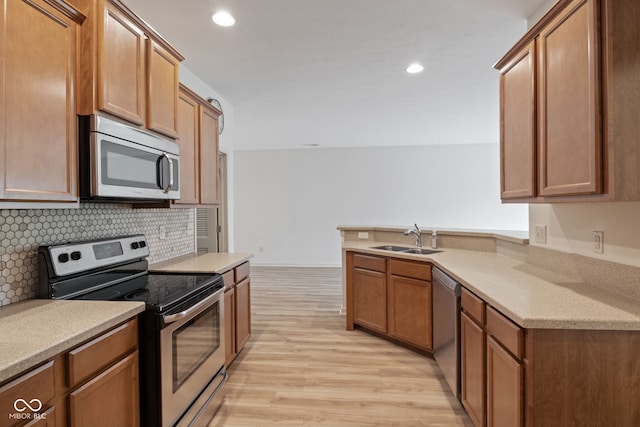 4261 Washington Blvd, Plainfield, IN 46168 - kitchen featuring appliances with stainless steel finishes, a sink, light wood finished floors, backsplash, and a peninsula